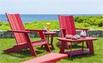 Two Red Contemporary Adirondack Chairs shown on the lawn with the ocean behind them.