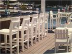 Seaside Casual MAD Bar Chair shown at a bar in white by the water.  